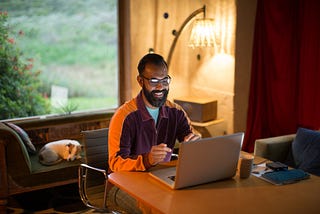 Mixed race man working from home on his computer, smiling