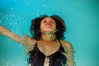 A person floating in a pool with their right arm outstretched.