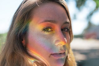 Woman with rainbow light on face.