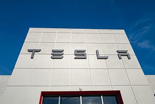 Low-angle view of the facade of Tesla Motors dealership with logo and sign in Pleasanton, California.