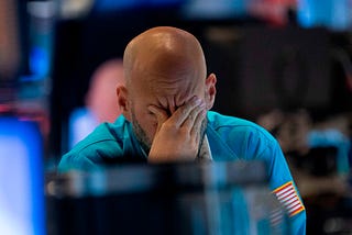 A photo of a trader wiping his eyes as he watches stock prices at the New York Stock Exchange.