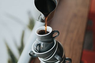 Pouring coffee into a precarious stack of cups