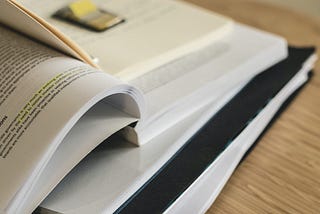 Photo of several open books stacked on one another.