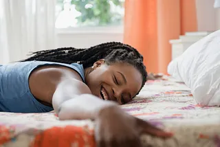 A woman smiling and hugging her bed.