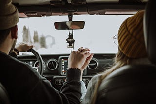 Man behind the steering wheel with woman in passenger’s seat.