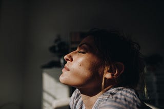 A young woman closes her eyes and breathes in, coping with loneliness and isolation.