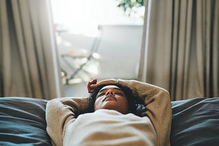 Black woman lying down with eyes closed.