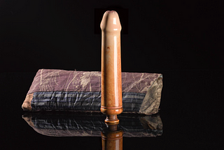 Photo of a highly polished dildo made of ivory and a cloth bag.