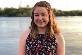 Ashley Broadwater, author, in a floral dress standing by a lake during sunset. #ashleybroadwater #sunset