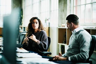 A woman discusses her idea in a meeting with a male colleague.