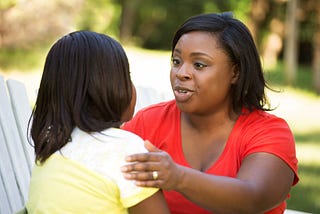 Black mother talking to her daughter outside.