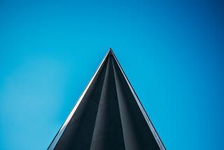 Low angle photo of a building, triangle is the focal point.