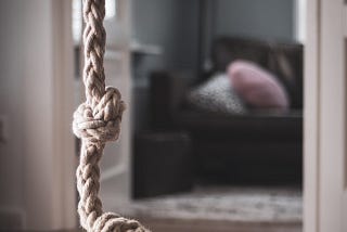 A rope hanging from the ceiling with a sofa in the background