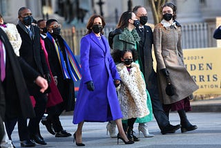 Harris wears a calf-length royal blue coat and Amara wears a furry knee-length leopard-print coat.