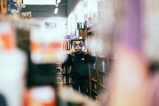 book things make readers happy man in shop holding cover showing a face up to his own face foreground is blurry man in focus