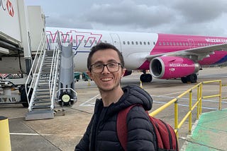 A man wearing a black jacket standing next to a Wizz Air A321 plane.