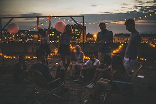 A photo of a rooftop party with garland lights.