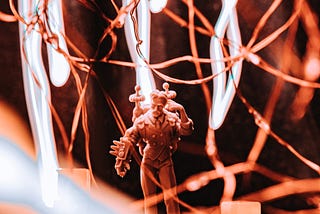 Nikola Tesla as a miniature from the board game, Monumental wrapped in fairy lights with long exposure LEDs in the background