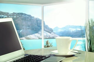 A laptop on a table overlooking a scenic getaway