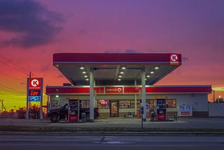 Photo of a Circle K glowing with the light of a beautiful sunset behind it