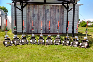 A row of the robots lined up in front of a shed.