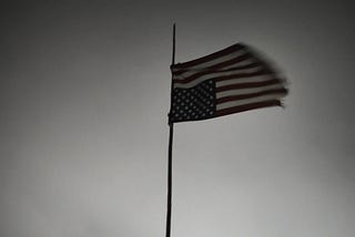 A photo of an upside down American flag hanging over a dark, ominous sky in Oceti Sakowin Camp.