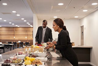 A photo of businesspeople getting food at a lunch buffett.