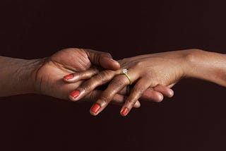 Closeup of a Black woman’s hand with an engagement ring.