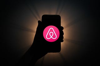 Airbnb logo is seen displayed on a phone screen
