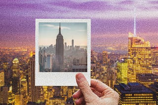 A hand holding a Polaroid photo of NYC up to the NYC skyline at evening.