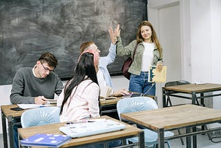 two students in a classroom high-fiving