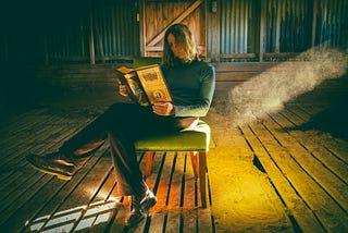 An incongruous photo of a woman reading Shakespeare in an abandoned pig shed.