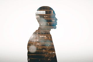 Profile view silhouette of businessman double exposed with city at night.