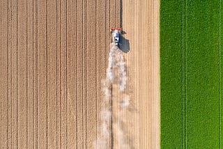 Overhead drone shot of a farm vehicle harvesting wheat.