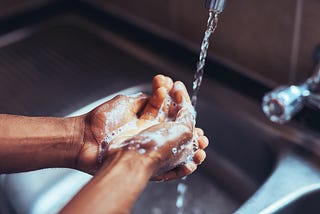 A close up hand washing in the kitchen sink.