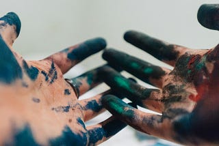 person hand with green and blue paint