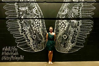 A photo of the author’s wife in front of a wall painting of wings.