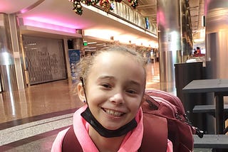 Young girl smiling and with backpack on waiting to take her first flight.