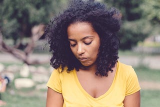An anxious woman looks down while at the park.