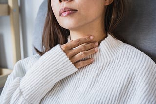 Photo of a woman putting her hand to her collarbone