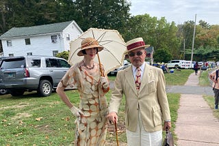 A woman with a parasol and her husband in knickers pose for the camera.