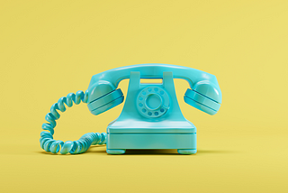 A photo of a teal old-fashioned phone against a yellow background.