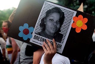 A photo of Breonna Taylor on a sign that a protestor is holding at a rally in Denver, Colorado.
