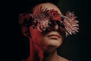 Photo of a man with his eyes covered by flowers.