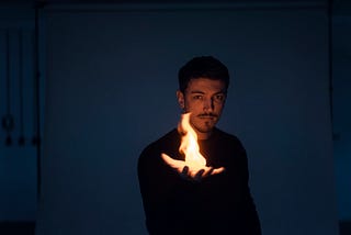A picture of a man holding out a flame in his open palm.