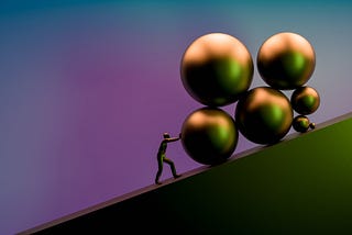 A man pushing several large balls of various sizes up an incline.