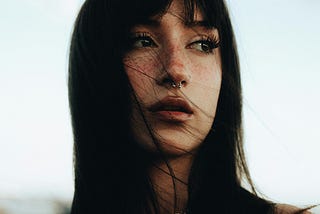 Portrait of a woman with dark hair staring into the distance.