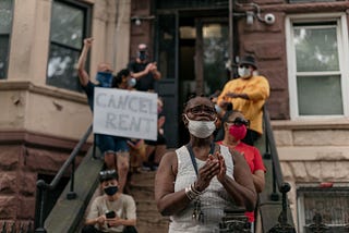 A group of housing activists in Brooklyn with a “cancel rent” sign. A Black woman stands in the front wearing a mask.