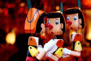 A close-up of 3 Pinocchio string puppets.