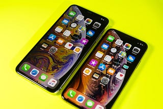 The new Apple iPhone Xs and Xs Max against a bright modern neon yellow background.
